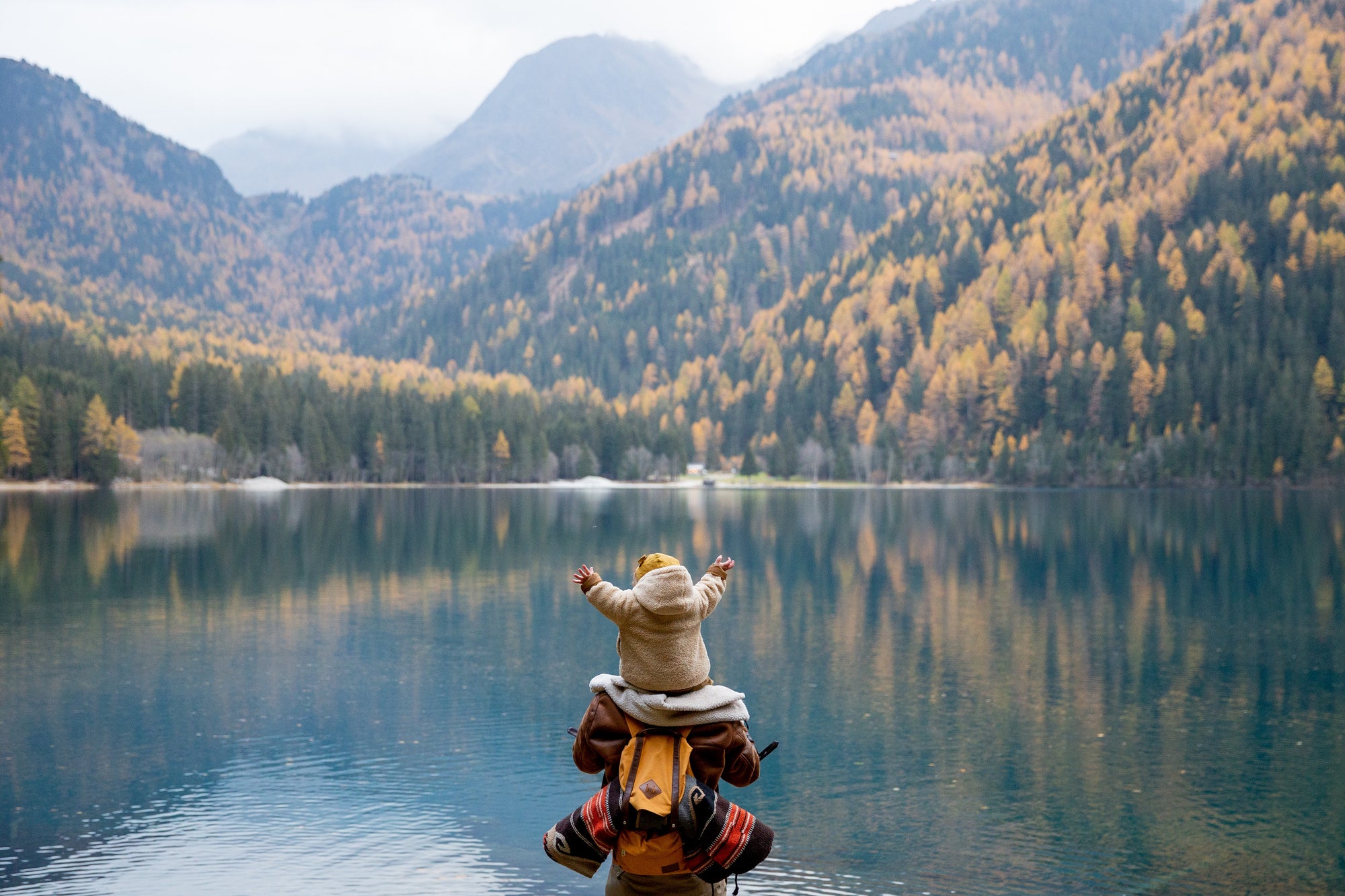 Child on parent's shoulder looking at lake view