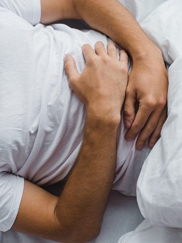 cropped shot of man in bed, suffering from stomach bug